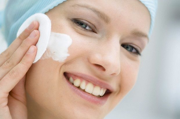 Young Woman face using a cleansing cotton on her cheek